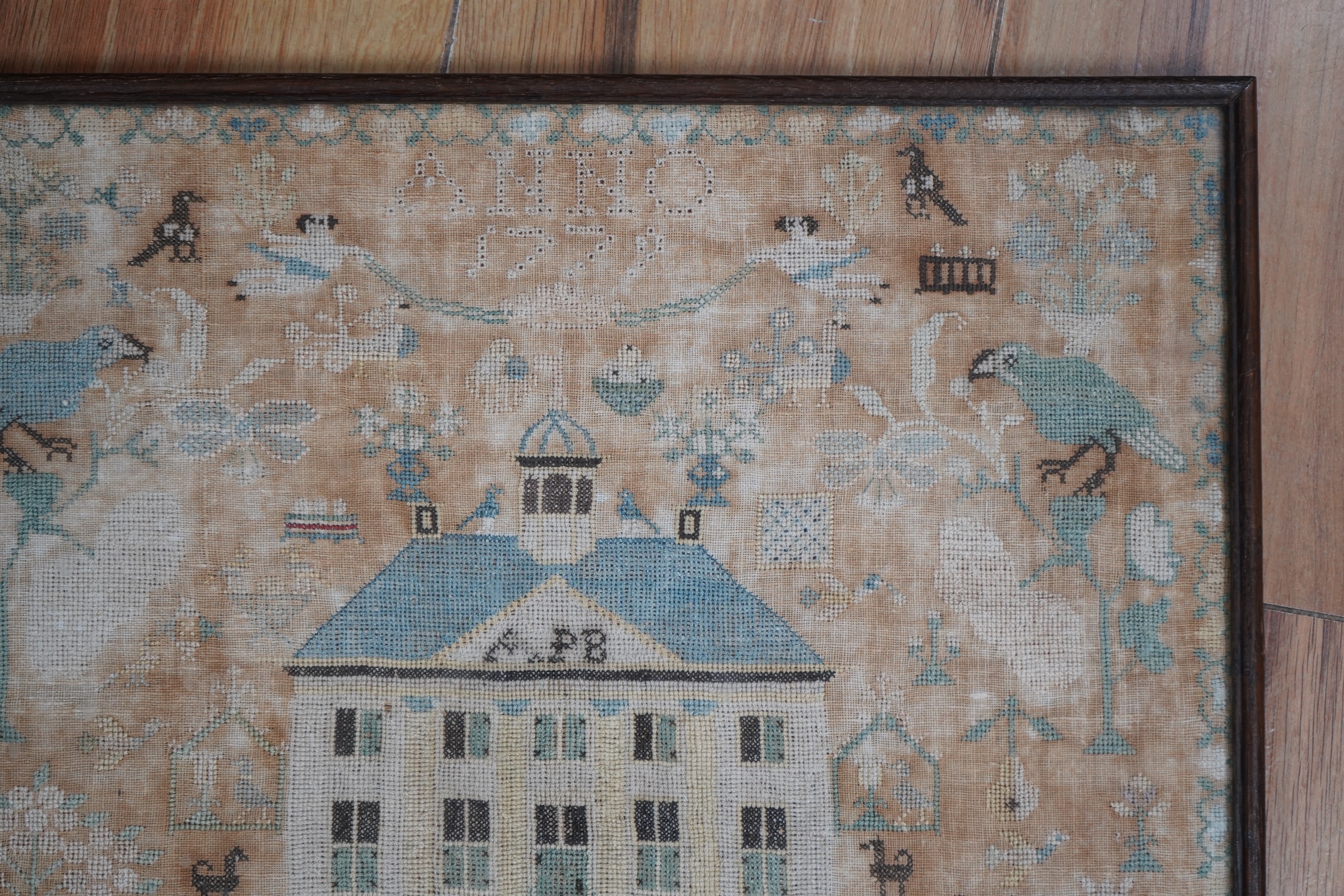 A framed 18th century sampler, dated 1779 by SS., worked in fine cross stitch with motifs of angels, figures, flowers, trees birds a fox and a stag surrounding a house with initials APB. 39cm x 37.5cm. Condition - the em